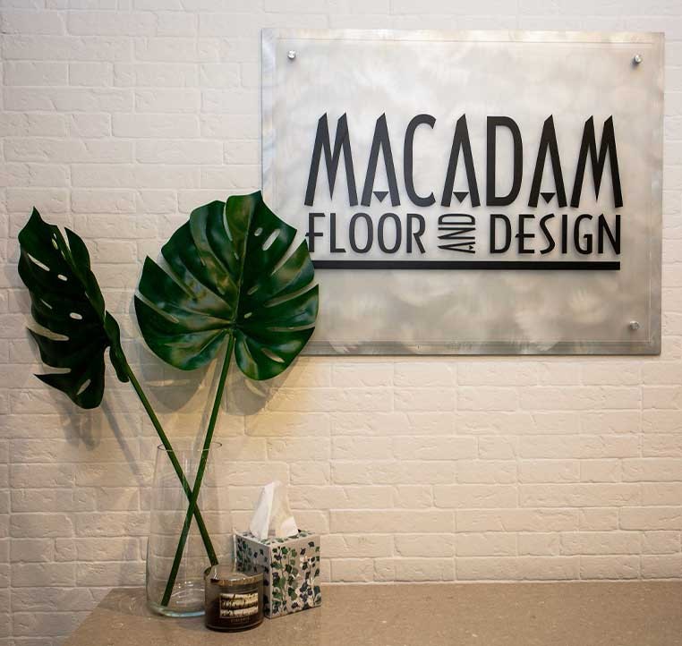 Macadam logo on a wall next to a plant